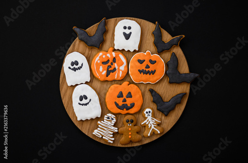 Halloween gingerbread cookies on a dark background. Bright homemade cookies for Halloween party - pumpkin, ghost, bat, mummy, skeleton. Halloween background with space for text. Top view. Mock up