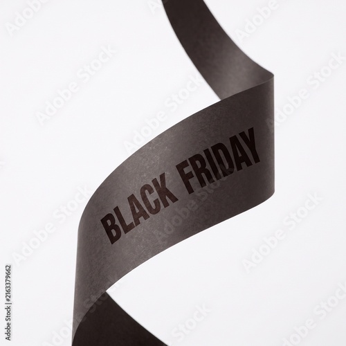 Black Friday text on a dark ribbon against a white background, representing sales and promotions