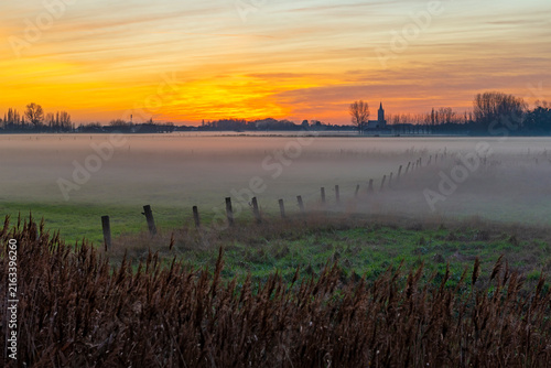 Foto Mist in field at sunset with church tower, West Flanders, Belgium
