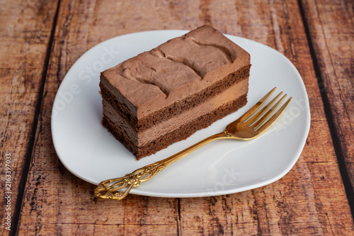 фотографія A glutenfree chocolate cream cake is cut and placed on a white plate