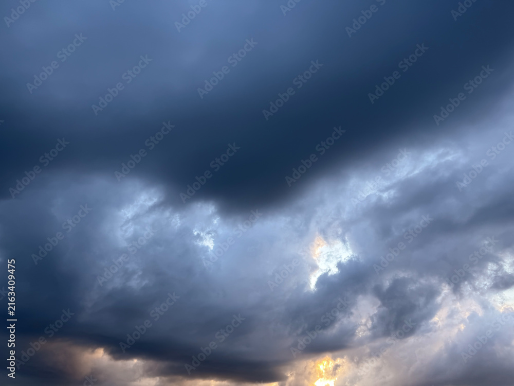 Obraz premium Dark storm clouds heavy sky background with patch of blue sky, dramatic thunderstorm cumulus cloudscape look like eye or heart, hope in crisis and conceptual breakthrough abstract nature wallpaper. 