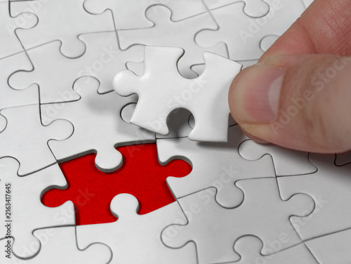 Closeup an male hand holding the jigsaw puzzle solution to the problem missing piece. Concept conceptual metaphor imagine.