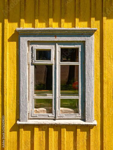 Old aged worn white window closeup exterior view wooden yellow house in the countryside