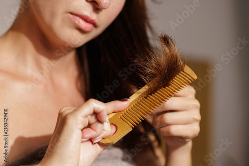 Canvastavla Woman examining damaged split hair ends on wooden comb