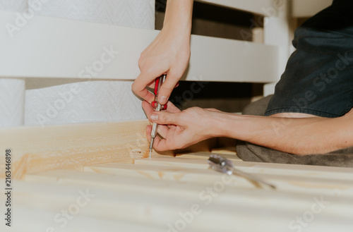 A young man installs a bunch of frame boards on a bunk bed.
