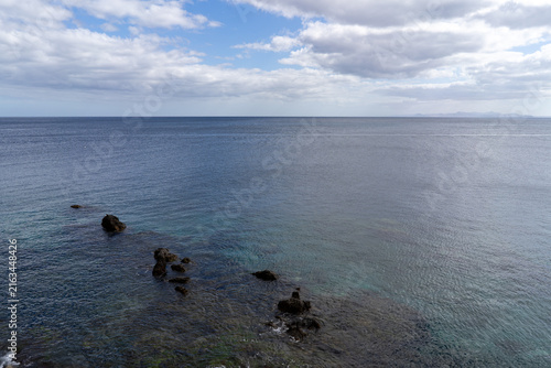 A serene ocean view off the coast of Lanzarote, showcasing the calm waters under a partly cloudy sky.