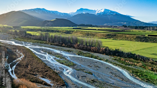 Looking down at the alpine braided water of the Ashburton river flowing to the sea through agricultural farmland