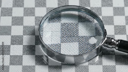 Magnifying glass on grey checkered background.