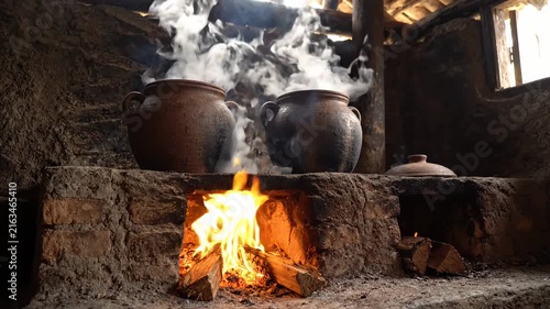 Traditional clay pots steaming over wood fire stove.