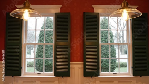 Twin windows with green shutters and hanging vintage lamps.