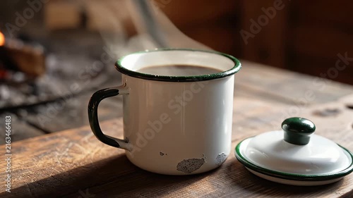 Vintage white enamel mug of coffee on rustic table.