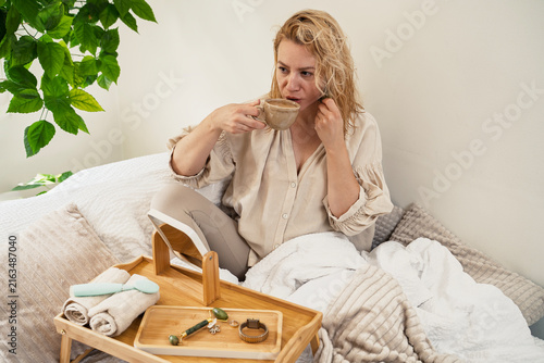 Woman in early forties having her morning beauty routing while drinking coffee 