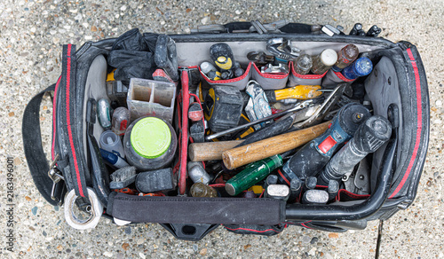 Handyman's open black tool bag illustrates construction tools on job site.