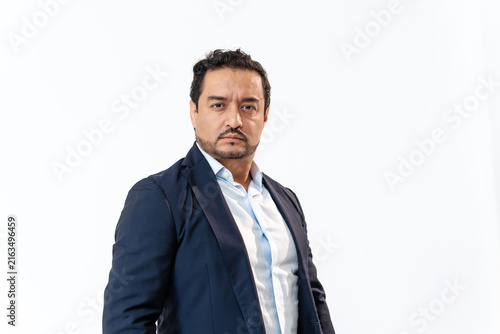 Latino businessman wearing suit standing confident against white background