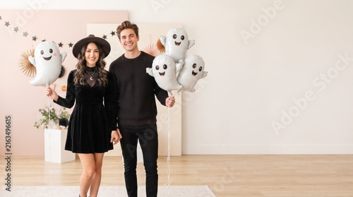 Happy couple holding ghost balloons for a fun Halloween celebration party