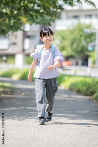 Plakat ランドセルを背負って歩く笑顔の小学生の女の子