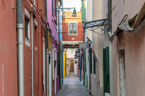 Obraz na plátně A narrow alley winds between colorful houses in Burano, Venice, Italy