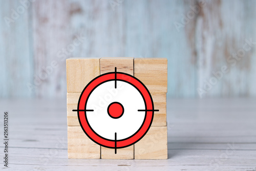 Precision scope reticle and target on wooden blocks; concept of focus and objectives featuring a bullseye symbol.