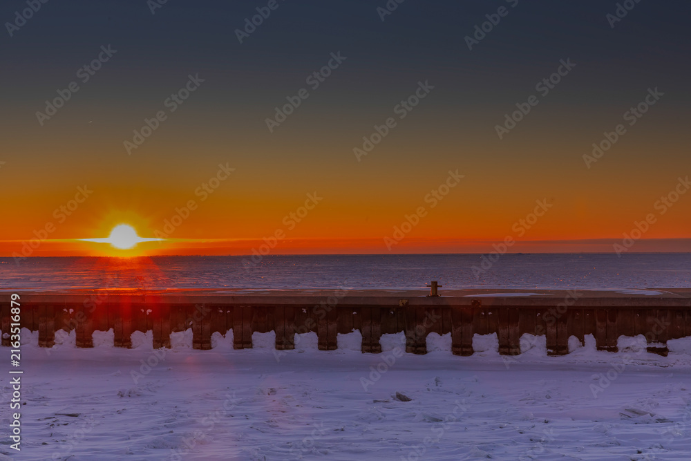 Fototapeta premium Winter sunrise over a frozen pier and Lake Erie at Port Dover, Ontario, Canada.