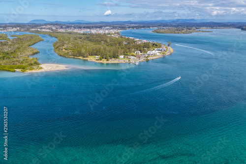 Aerial view from Settlement Point looking along the Hastings River towards Port Macquarie, showcasing the broad waterway, foreshore, surrounding coastal landscape and urban area in the distance