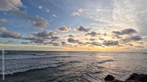 A wide evening timelapse shows strong waves crashing on breakwaters with a beautiful orange sunset over the horizon on the coast of Sri Lanka.