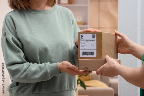 Young woman receiving parcel boxes from courier at doorway