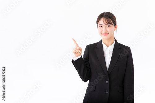 指をさす若いスーツの女性
