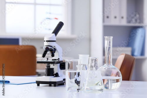 Microscope and glassware of water samples on table in research laboratory