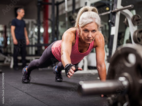 Fotografía Determined senior woman performing a challenging one-arm push-up exercise in a modern gym