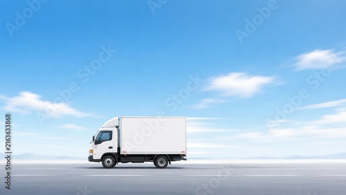Modern white delivery truck speeding on a highway under blue sky