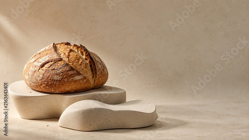 Artisan sourdough bread loaf on sculptural ceramic forms with warm neutral background and copy space