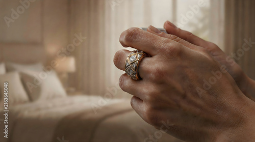 Close-up shot of aged hands wearing large ornate rings in a softly lit bedroom setting