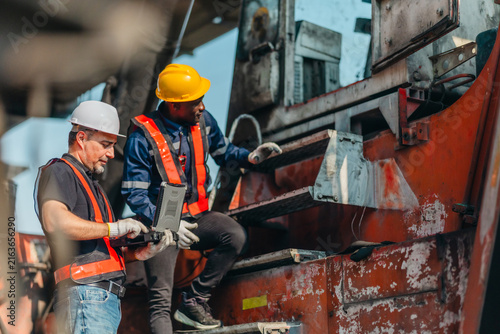 Industrial worker wearing hard hat and safety vest inspecting machinery and equipment at work site