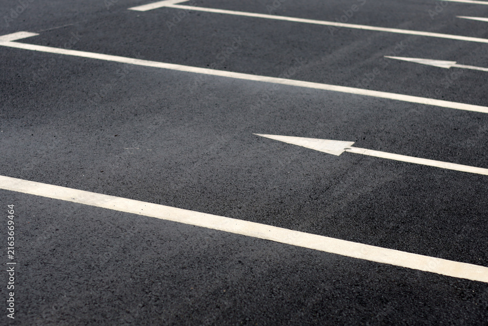 Fototapeta premium Empty outdoor parking spaces with white directional arrows.