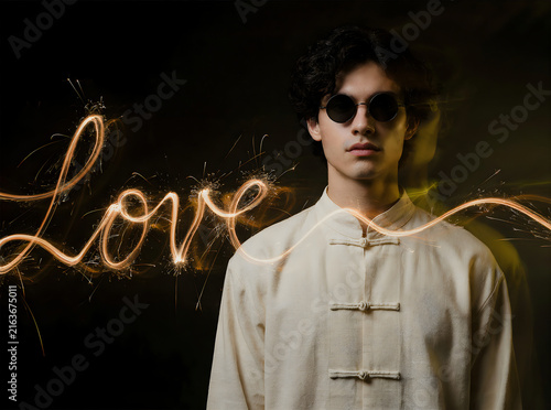 Mysterious portrait of a young man with sunglasses surrounded by glowing sparks spelling out 