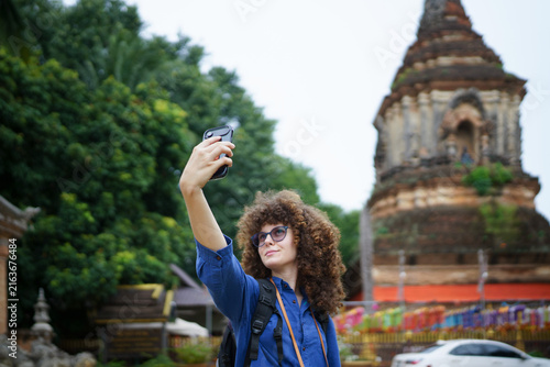 Young Woman Tourist Taking Selfie at Ancient Buddhist Temple in Chiang Mai Thailand, ideal for travel, tourism, and lifestyle campaigns.