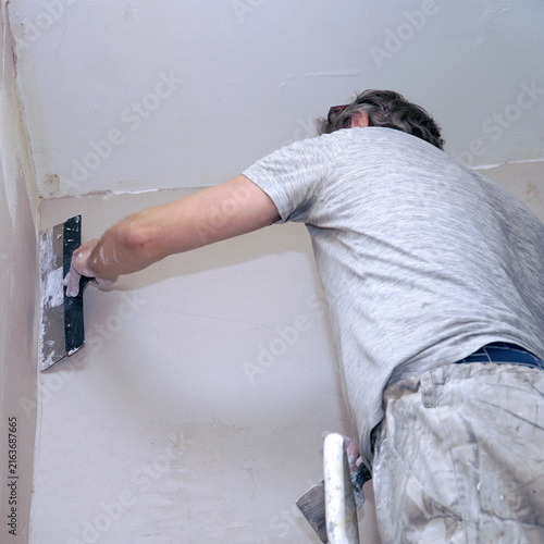 A man plastering a wall with a spatula