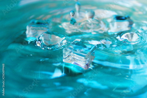Clear Ice Cubes In Turquoise Water With Splash And Ripple Texture