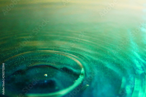 Concentric Water Ripples on Green and Gold Liquid Surface Close Up