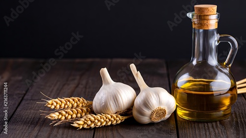 Fresh garlic bulbs with wheat and olive oil on rustic wooden table