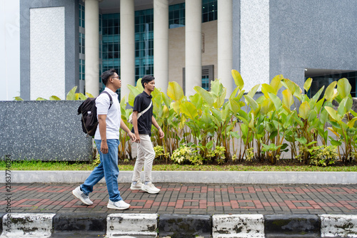 Two College Students Walking Together Outside Modern University Building