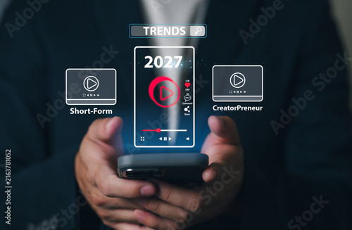 A Person holding a smartphone with a digital display showing upcoming trends Video Short-Form & Creator Preneur in 2027, including media icons, trend labels, and a futuristic interface.
