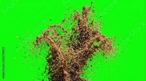 Explosion of brown sand and dirt particles over a green background