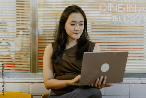 Asian woman freelancer sitting in coffee shop working late with his laptop.