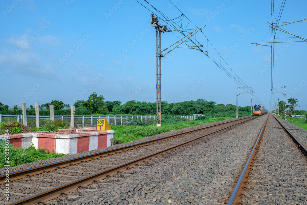 Fototapeta premium Saffron coloured Vande Bharat Express near Pune India. This is a made in India train set and also known as Train 18.