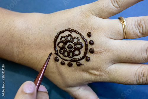 Woman Applying Fresh Mehndi Henna Design On hand With care