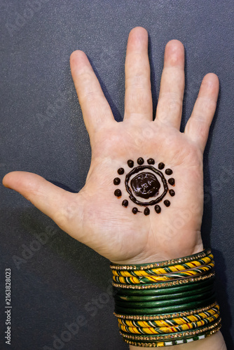 Woman Applying Intricate Mehndi Design On Palm With Henna Cone