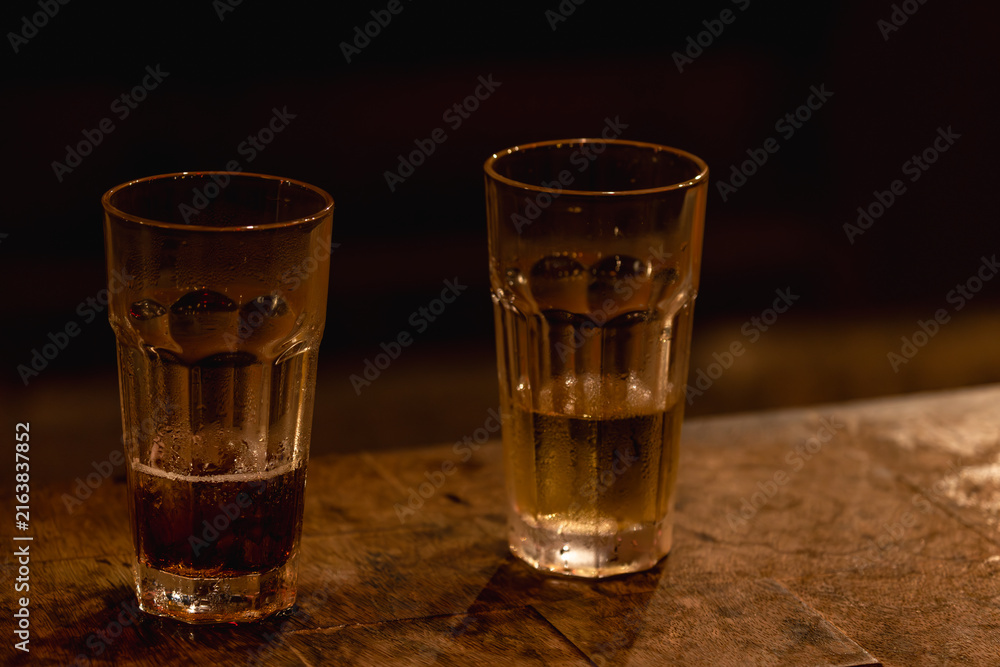 Naklejka premium Two Drinking Glasses on a Warm Wooden Table