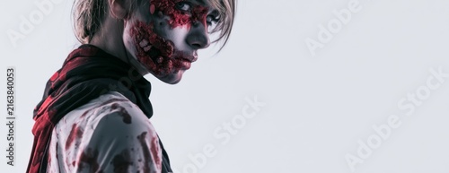 Person in a zombie costume for Halloween against a plain background  