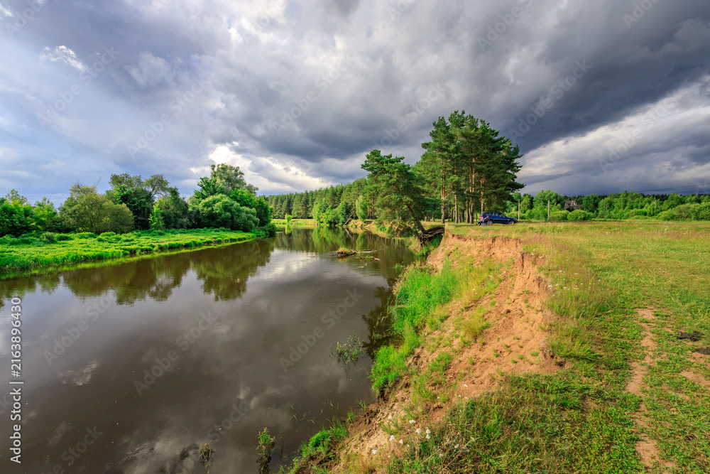 Fototapeta premium River reflects stormy sky under thick cloud cover